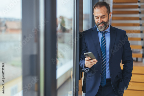 Shot of a young businessman using a smartphone in a modern office. Cropped shot of a mature designer texting on a cellphone in an office. Using the smartest tech to match his startup needs photo