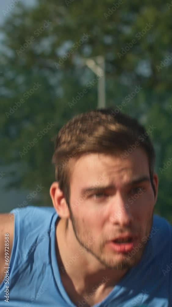 Vertical video of focused and determined young male athlete running during training in the outdoor stadium, tracking close up shot. Vertical video of focused and determined young male athlete running during training in the outdoor stadium, tracking close up shot.