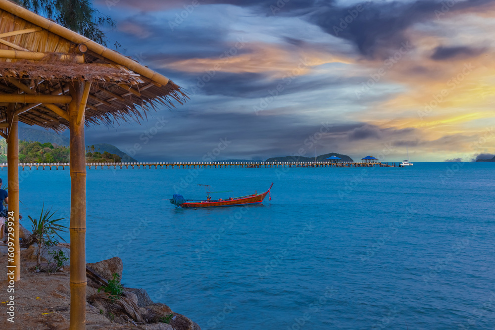 Colourful Skies Sunset over Rawai Beach in Phuket island Thailand. Lovely turquoise blue waters, lush green mountains colourful skies and beautiful views the pier and longtail boats and islands 