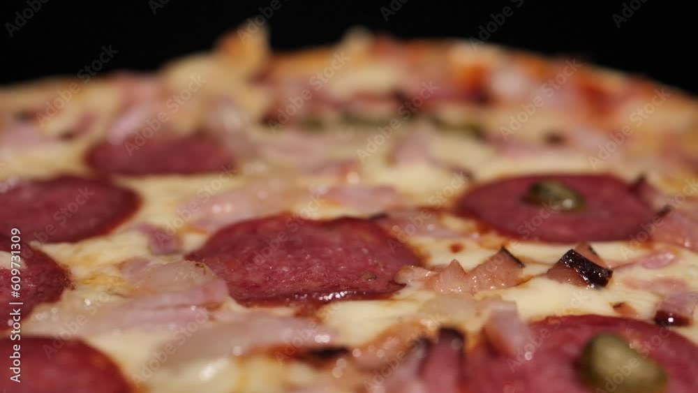 Pizza with salami and sliced bacon pieces. Homemade pizza on a turntable. Pizza with salami and sliced bacon pieces. Homemade pizza on a turntable.