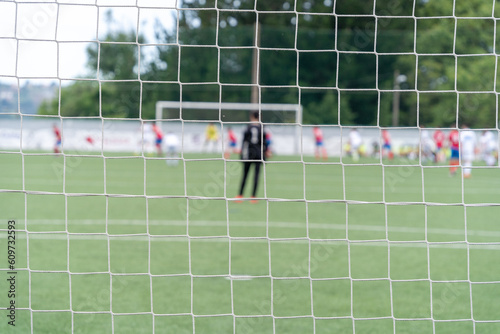 Soccer goal mesh focused on a match with the goalkeeper and players out of focus. . High quality photo