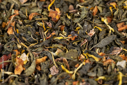 A large amount of dry green tea with pieces of fruit