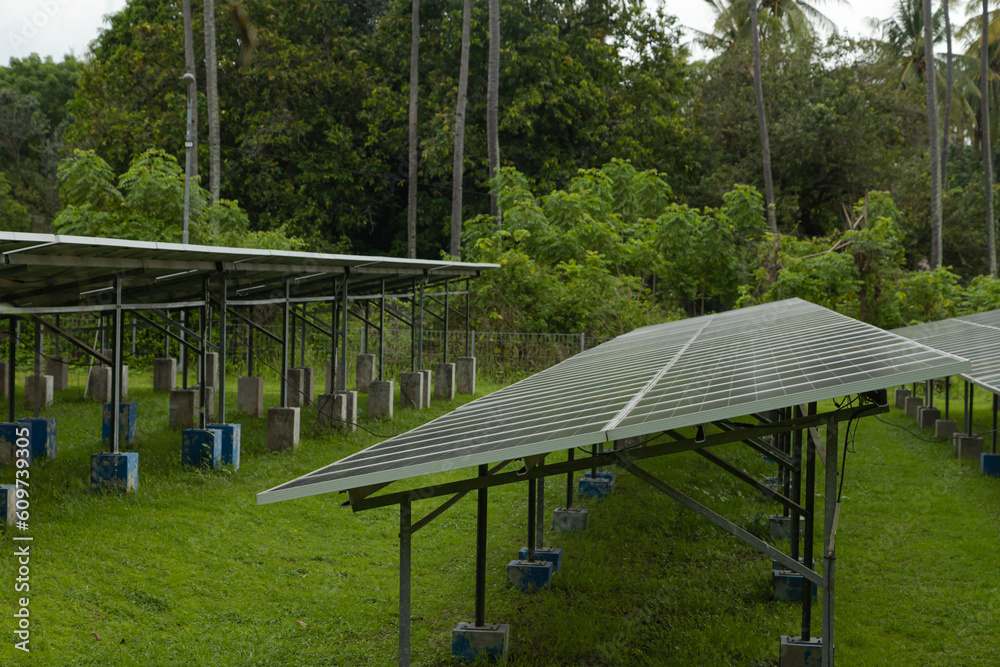 Fototapeta premium Solar power plant energy panels on tropical island Gili Air, Indonesia. Cloudy day, tropical forest