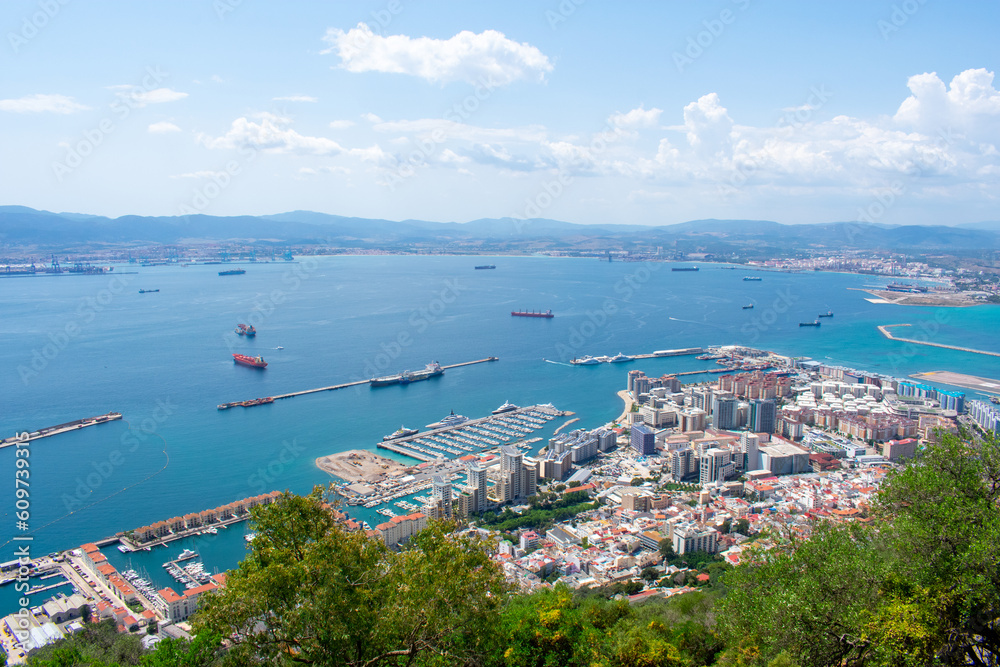 Gibraltar, Aerial view on buildings, city and coast of sea. Crystal clear blue water against mountains Gibraltar, Aerial view on buildings, city and coast of sea. Crystal clear blue water against mountains