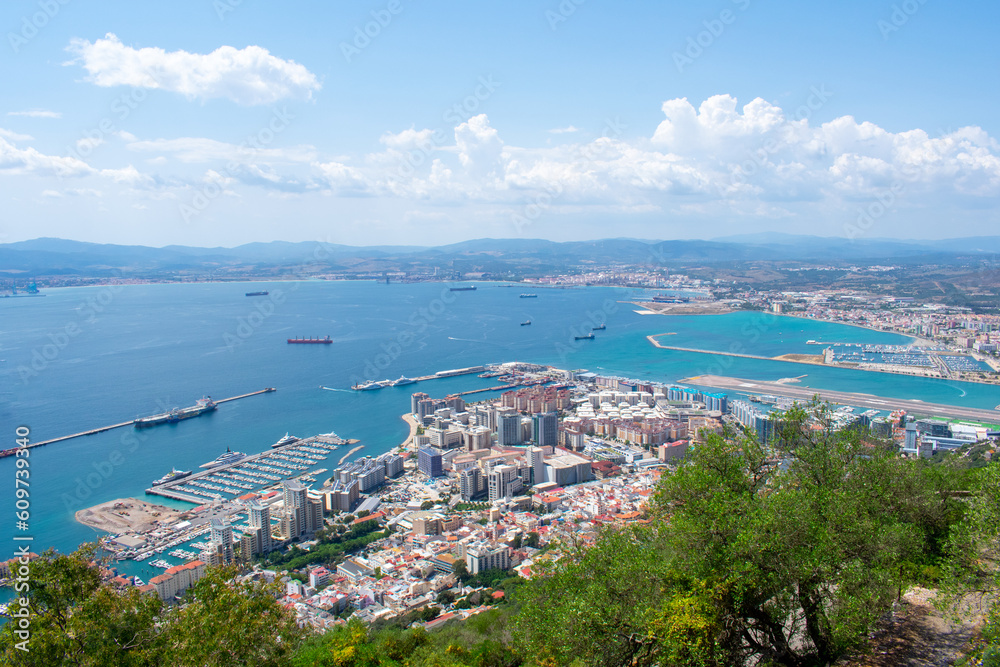 Gibraltar, Aerial view on buildings, city and coast of sea. Crystal clear blue water against mountains