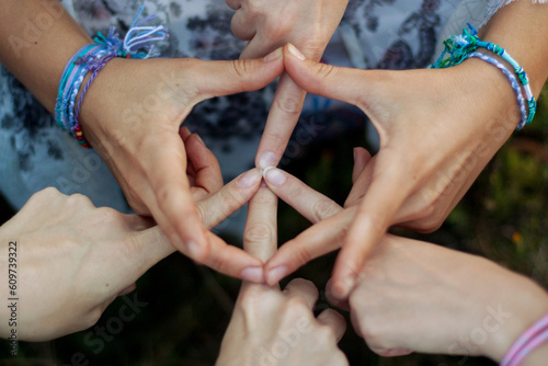 Pacific sign made from three pairs of female hands. The girls wrists are decorated with bracelets made of threads and beads. Youth culture, gesture, hippie and peace concept.