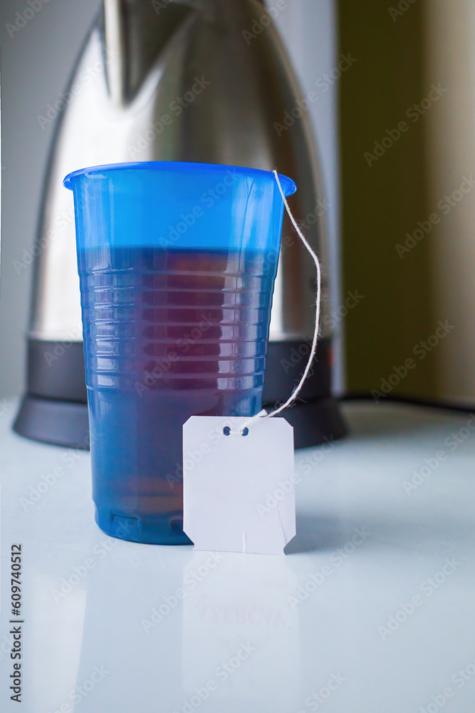 plastic cup with tea on the background of an electric kettle plastic cup with tea on the background of an electric kettle