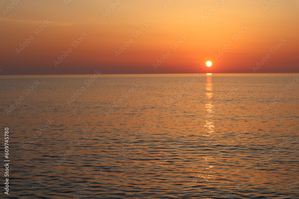 Sunset over the sea, water and sky and orange sun