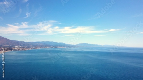 Aerial view over the turquoise mediterranean looking towards the mountainous mainland of Andalusia and the Costa del Sol, Estepona, Marbella, Manilva, Malaga, Spain