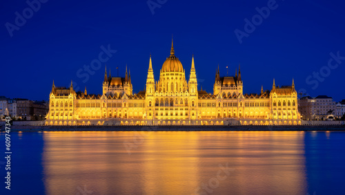 Parliament building in Budapest, Hungary. Parliament and reflections in the Danube River. Blue hour and evening illumination of the building. High resolution photo.