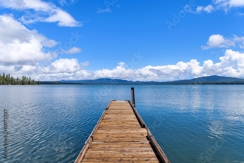 Boat Ramp at Blue Mountain Lake - A long wooden boat ramp extending onto a blue mountain lake under Spring blue sky and white clouds. Crane Prairie Reservoir  Bend  Oregon  USA.