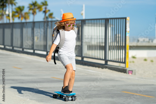 Kid boy riding skateboard in the road. Kid practicing skateboard. Children learn to ride skateboard in a park on sunny summer day. Kid skating on skateboard.