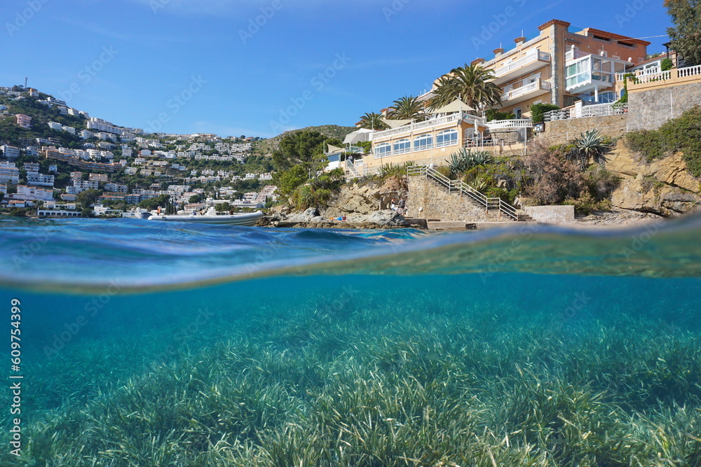 Coastal hotel on the shore of the Mediterranean sea in Spain with seagrass underwater, split view over and under water surface, Costa Brava, Roses town, Catalonia