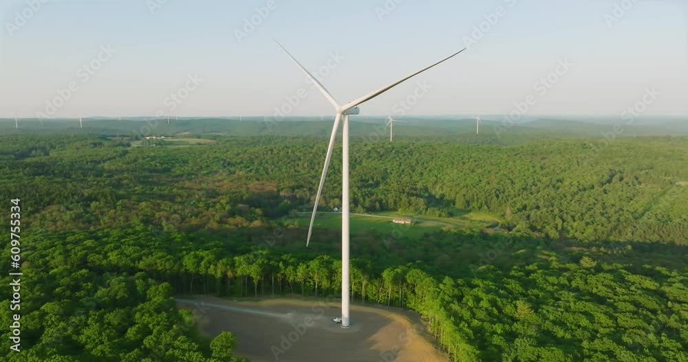 Early morning or late afternoon aerial drone view of wind power turbines under construction, on a green forest. Wind turbines are part of the energy transition strategy Early morning or late afternoon aerial drone view of wind power turbines under construction, on a green forest. Wind turbines are part of the energy transition strategy