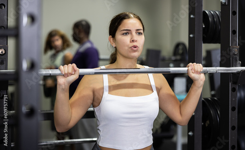 Caucasian woman doing reps with barbell using half rack