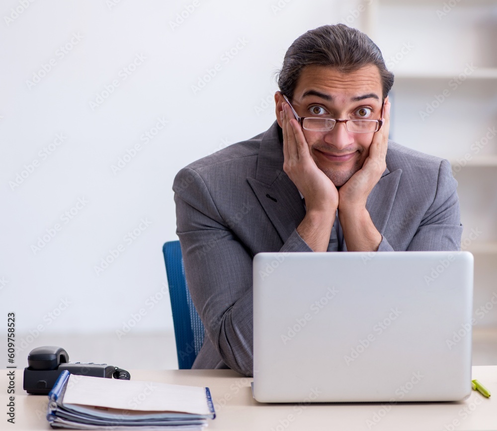 Young male employee unhappy with excessive work in the office Young male employee unhappy with excessive work in the office