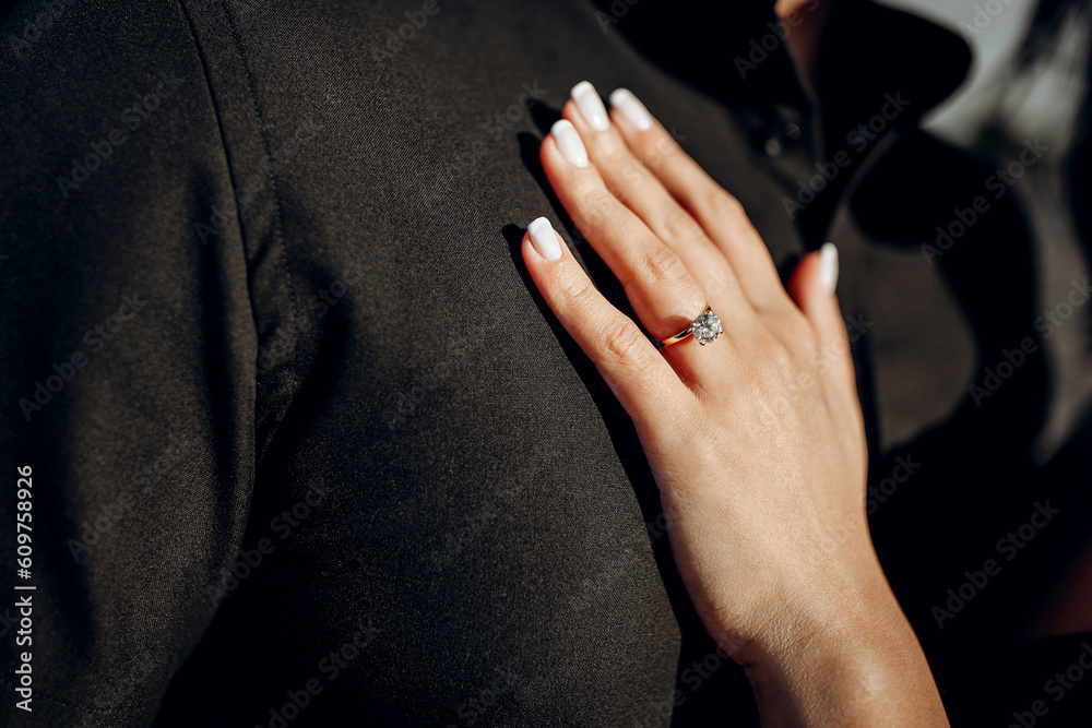 Engagement ring with a precious stone on a woman's finger close-up. A woman's hand with a wedding ring on the chest of a beloved man. An offer of marriage. Man wearing a black shirt