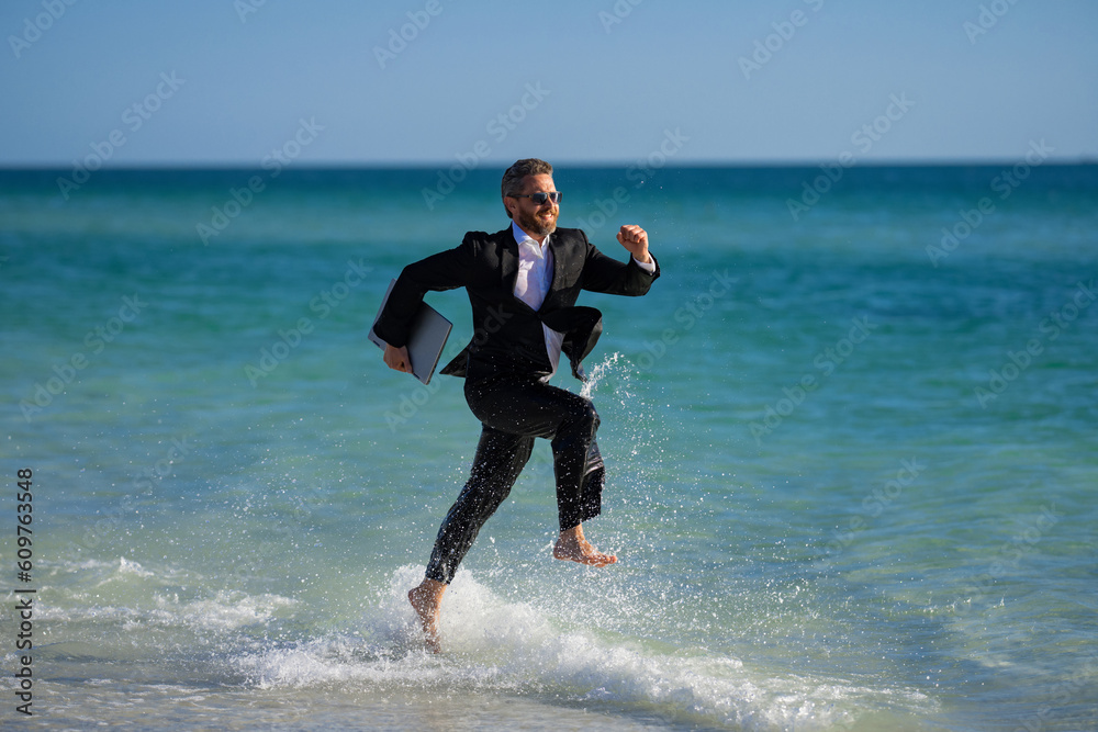 Summer business. Freelancer on summer sea beach. Business man in wet suit in sea water. Crazy business vacation. Funny businessman with laptop in formal wear near tropical beach. Hot business summer. Summer business. Freelancer on summer sea beach. Business man in wet suit in sea water. Crazy business vacation. Funny businessman with laptop in formal wear near tropical beach. Hot business summer.