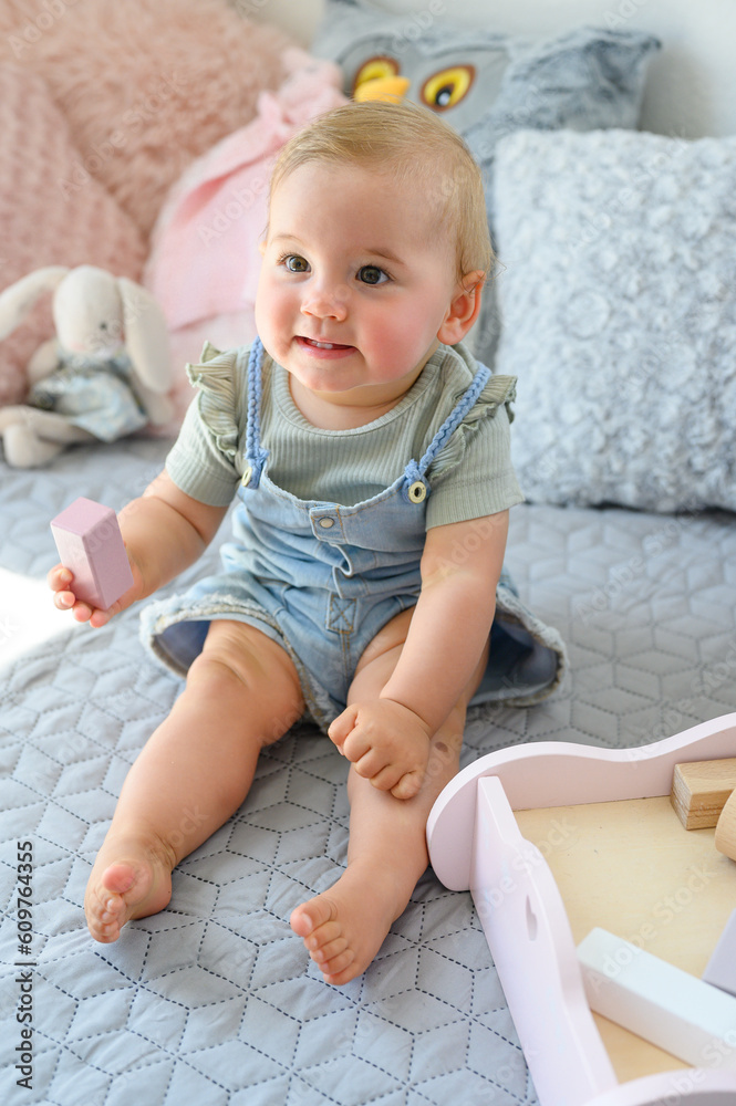 Cute baby sitting on bed and looking away Cute baby sitting on bed and looking away