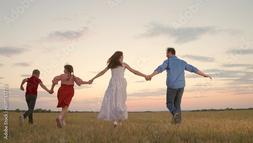 Dad mom child, son, daughter run together. Children, child, together with their parents run in park, sunset. Happy family, child summer weekend. Healthy family. Fun children run. People play in nature