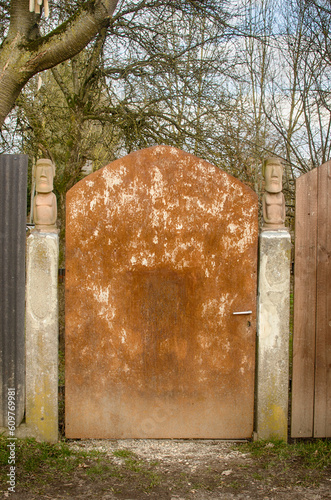 Rusty Gate in Private Courtyard with Decorative Statuettes 'Tam Tam' - Easter Island Moai Sculptures