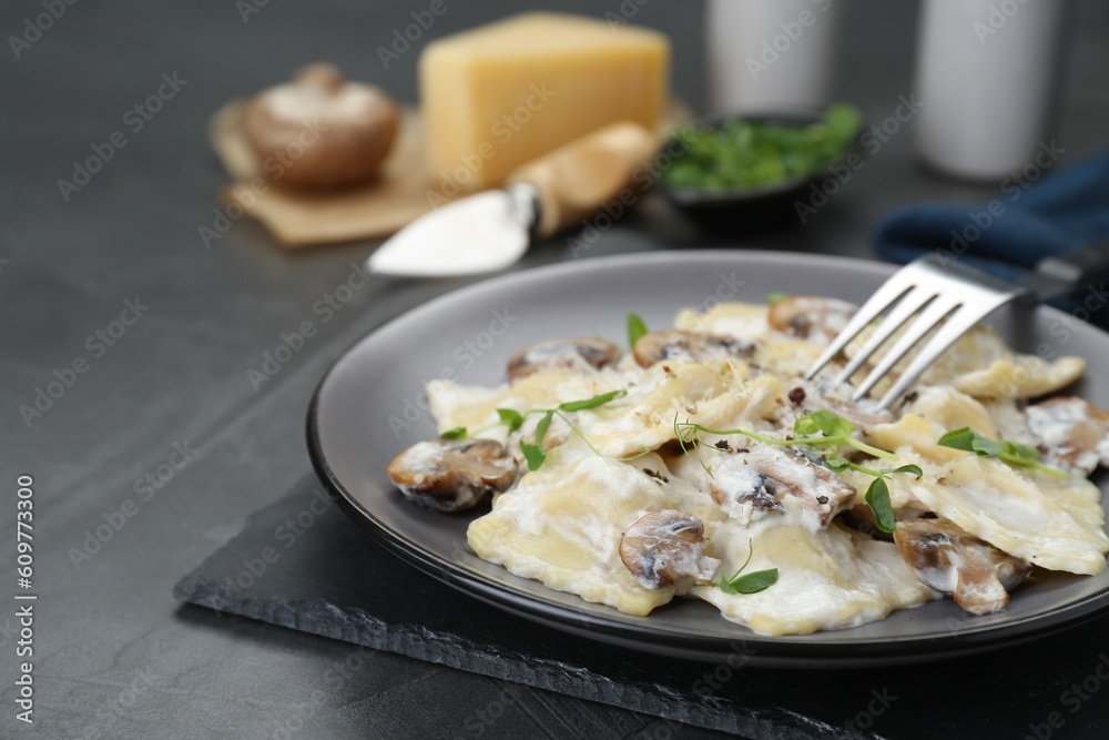 Delicious ravioli with tasty sauce and mushrooms served on black table, closeup Delicious ravioli with tasty sauce and mushrooms served on black table, closeup