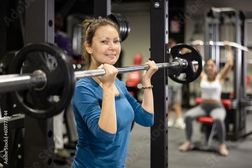 Sportswoman doing exercises with a barbell in the gym