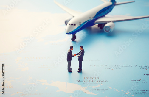 世界地図の上の飛行機と握手をするミニチュア photo