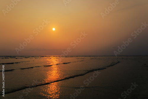 Beautiful sunset view of the beach with orange sky and golden reflections.