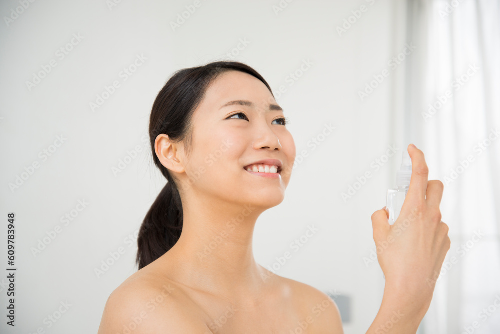 顔にスプレーをしているすっぴんの女性 顔にスプレーをしているすっぴんの女性