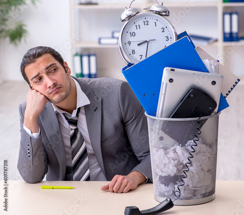 Fired young businessman with recycle bin in time management conc photo