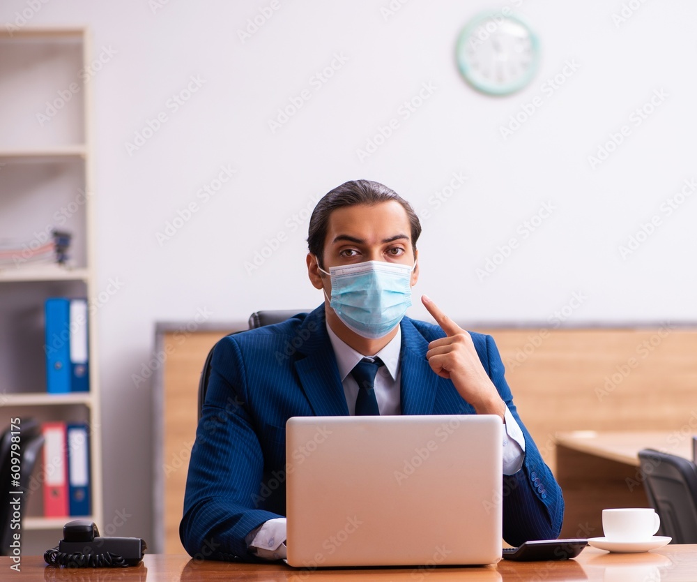 Young male employee working in the office wearing mask Young male employee working in the office wearing mask