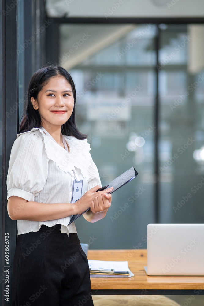 Fototapeta premium Young beautiful joyful happy woman employee officer business smiling while working, cute asian woman professional possibly accountant, happy interest manager bookkeeping firm law