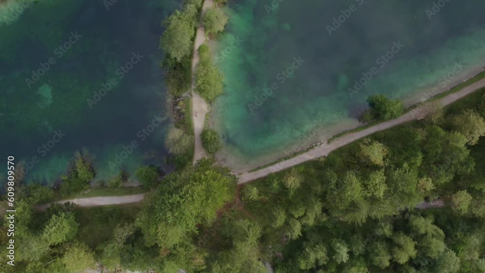 Lake Bluntausee in austria with cyclist riding on small path between the lake, aerial