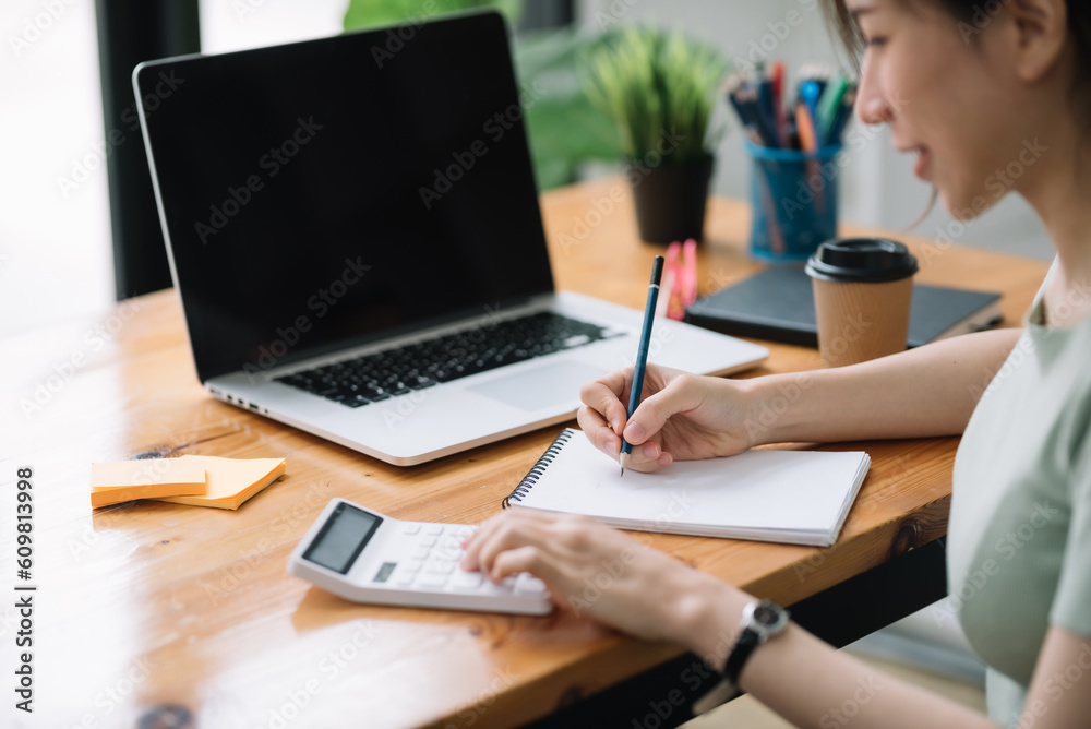 Close-up of businesswoman hands using a calculator to check company finances and earnings and budget. Business woman calculating monthly expenses, managing budget,  papers, loan documents, invoices.