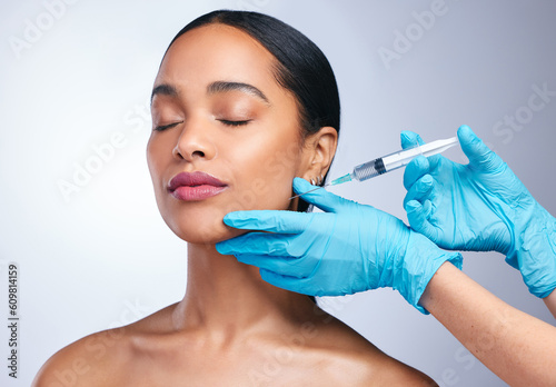 Woman  studio and gloves with needle  surgery or cosmetics for skin  facial or collagen by white background. Girl cosmetic surgeon and filler on face  syringe or hands for beauty  skincare or change