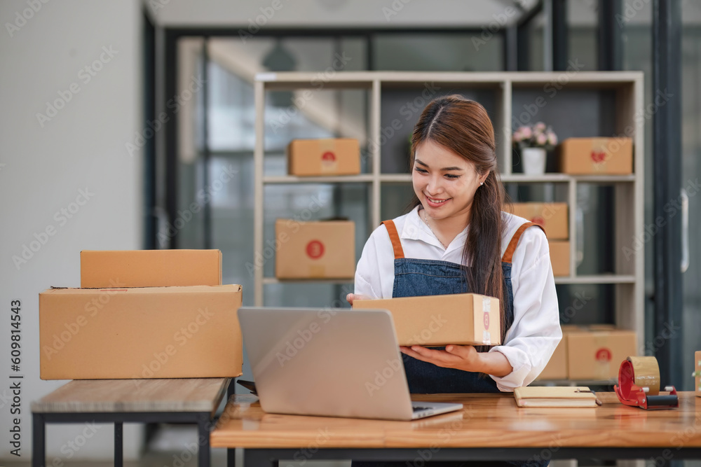 Startup happy Asian woman business owner works with a box at home office. prepare parcel delivery SME supply chain, procurement, package box to deliver to customers, Startup happy Asian woman business owner works with a box at home office. prepare parcel delivery SME supply chain, procurement, package box to deliver to customers,