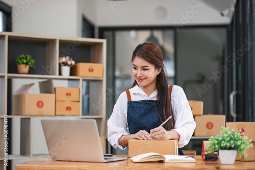 Portrait business woman smile and use tablet checking information on parcel shipping box before send to customer. Entrepreneur small business working at home. SME business online marketing.