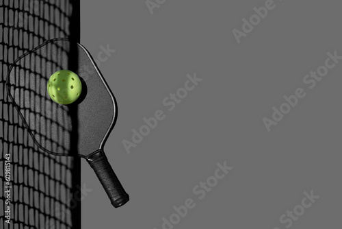 Flatlay of a pickleball paddle and ball on gray
