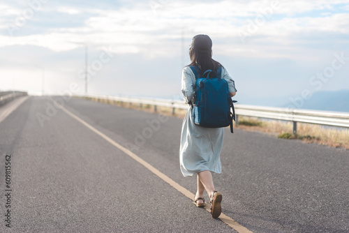 Rear view of woman traveler with backpack walking on road japanese mood with blue sky