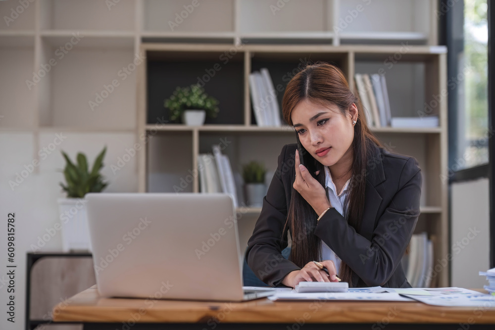 Asian businesswoman in formal suit in office happy and cheerful during using smartphone and working Asian businesswoman in formal suit in office happy and cheerful during using smartphone and working