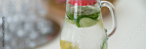 Drink with lemon slices and cucumber in jug on table. Mint summer chilled lemonade photo