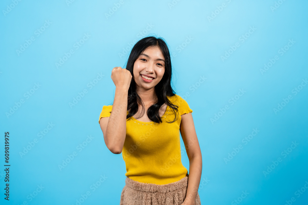 Portrait, Asian women long hair wearing t-shirt, having happy expression focus on what is expected, with fists clenched raised handshigh face with pride joy, Isolated indoor studio on blue background. Portrait, Asian women long hair wearing t-shirt, having happy expression focus on what is expected, with fists clenched raised handshigh face with pride joy, Isolated indoor studio on blue background.