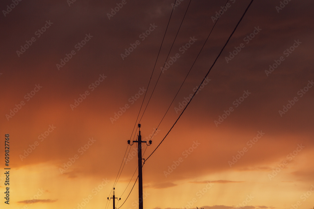 High-voltage power lines at sunset. Electricity distribution station. Electricity pylons on the background of the sky.
