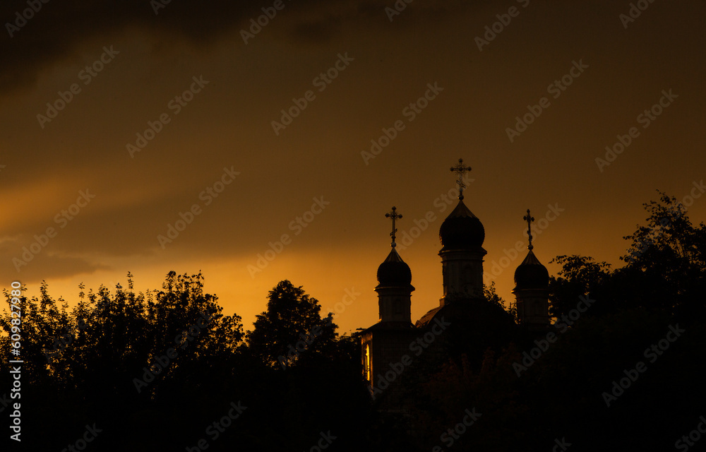 The silhouette of the domes of an Orthodox Christian church in Romania against the background of the red sky. Faith or religion concept photo