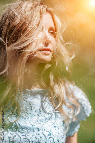 Fototapeta Naklejka Na Ścianę i Meble -  Blond garden. Portrait of a blonde in the park. Happy woman with long blond hair in a blue dress.