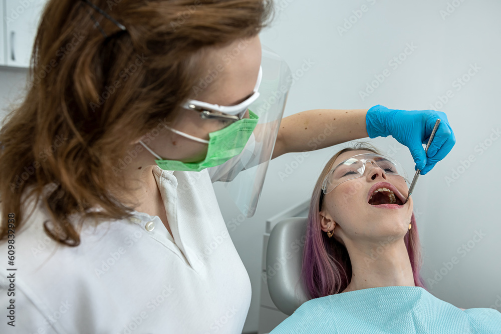 European young woman sits in a medical chair while a dentist fixes her teeth in a dental clinic European young woman sits in a medical chair while a dentist fixes her teeth in a dental clinic
