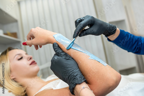 beautician applies hair removal gel to the client s hand