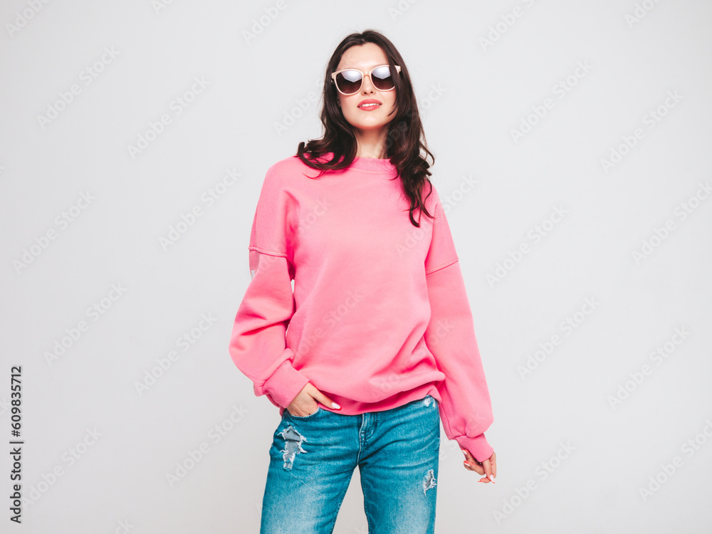 Young beautiful smiling female in trendy summer jeans and pink sweater clothes. Sexy woman isolated on white in studio. Positive model. Cheerful and happy. In sunglasses Young beautiful smiling female in trendy summer jeans and pink sweater clothes. Sexy woman isolated on white in studio. Positive model. Cheerful and happy. In sunglasses