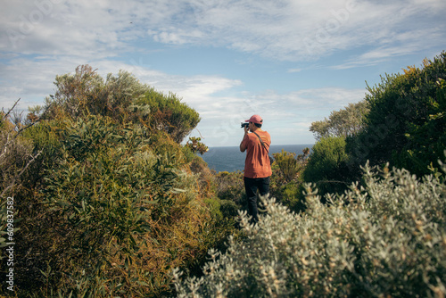 a man taking a photo into the bushes od western Australia with the turquoise Indian ocean.
